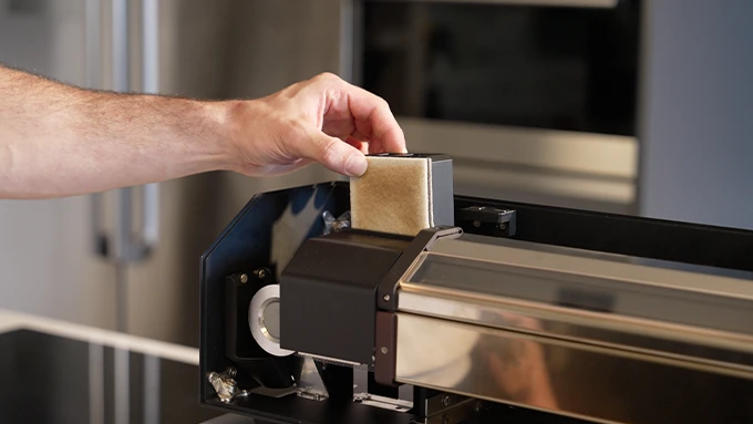 A hand removing the ROASTREAM filter for maintenance